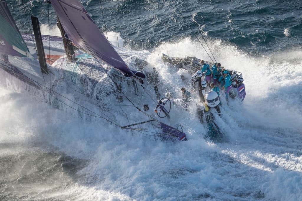 Sailing team being hit by a wave during a race.