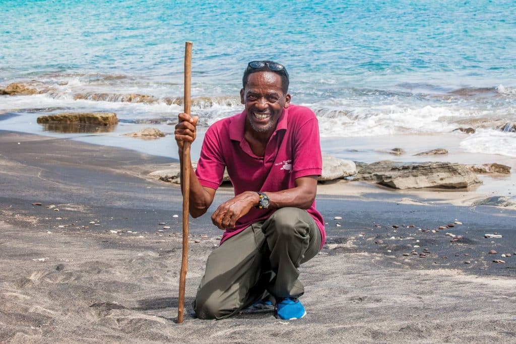 man in pink shirt on beach with stick