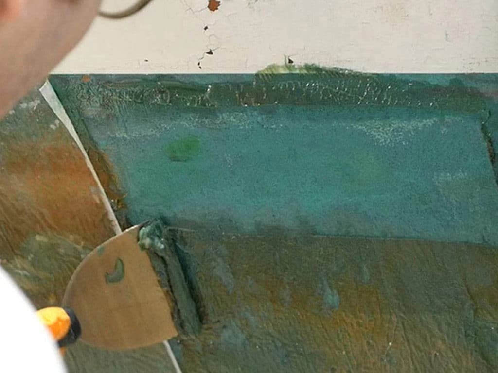 Scraping stripped paint from a boat hull