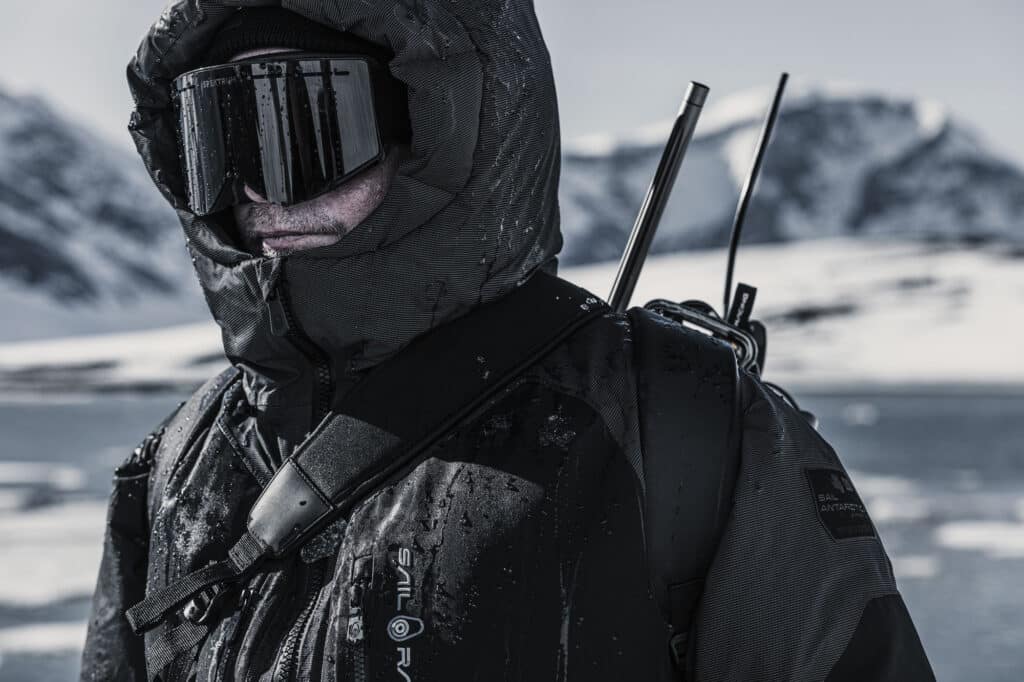 man wearing arctic clothing, hood, ski goggles, gas