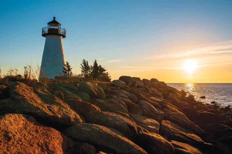 YTG1122_Nautical-Life_6 A lighthouse overlooking a rocky shore during a sunset